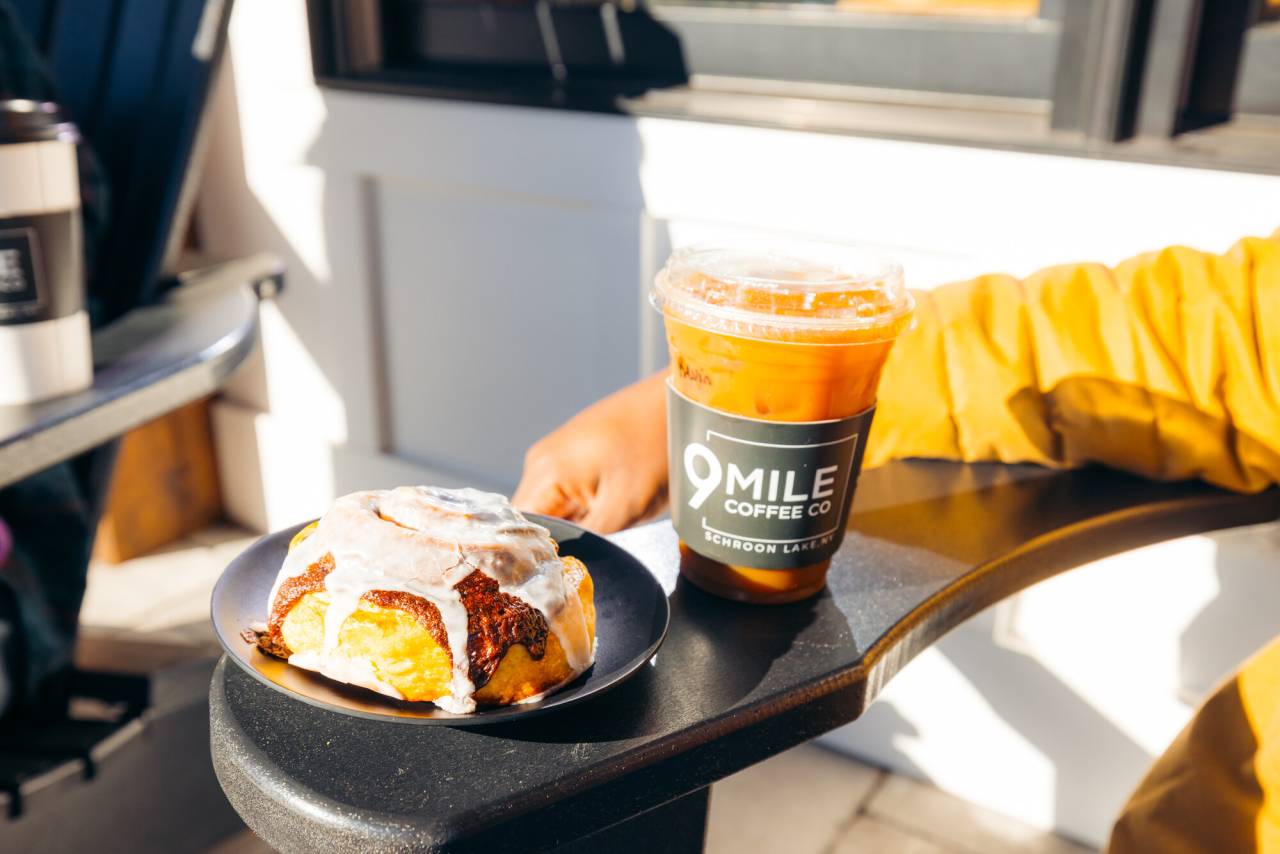 A coffee and cinnamon bun on an Adirondack chair. 